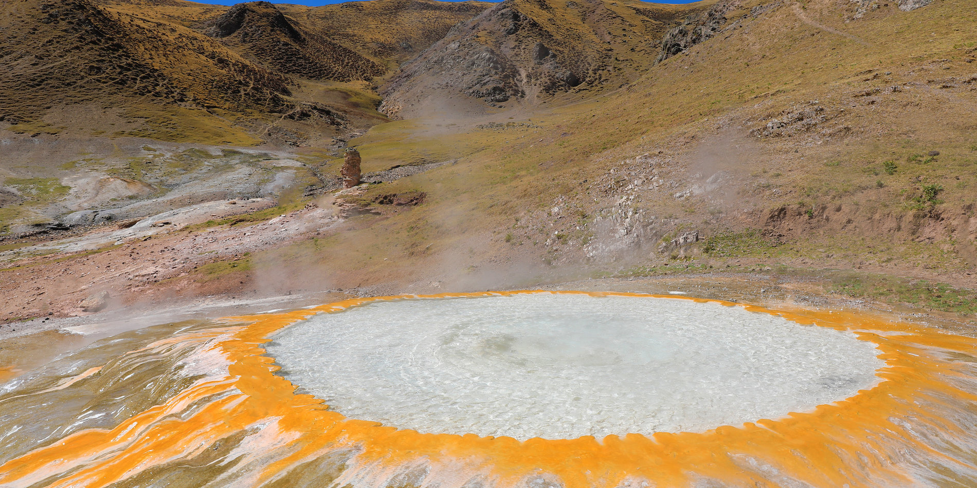 Steaming hot spring with mountains in background
