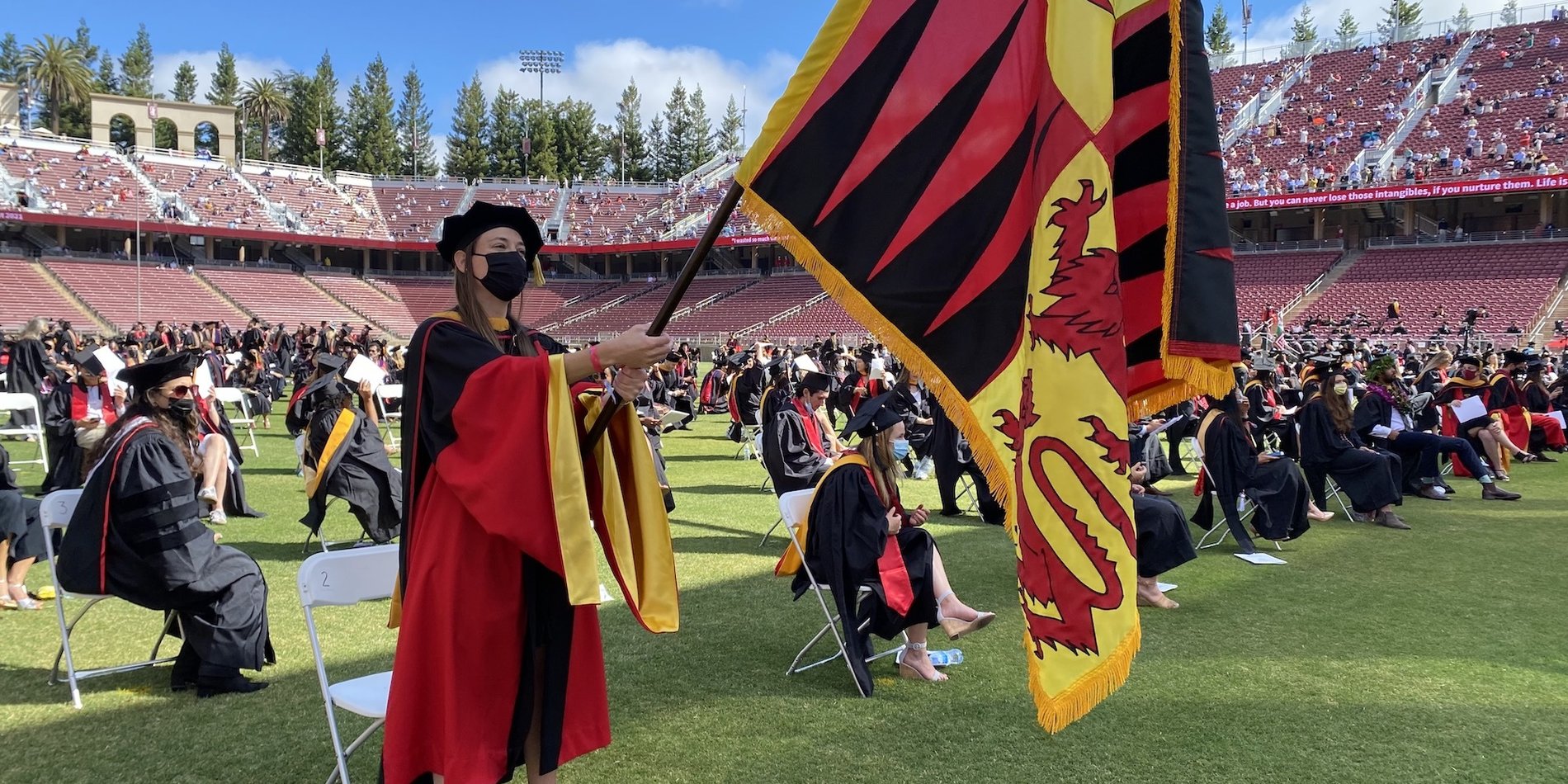 Graduate waving school flag in stadium