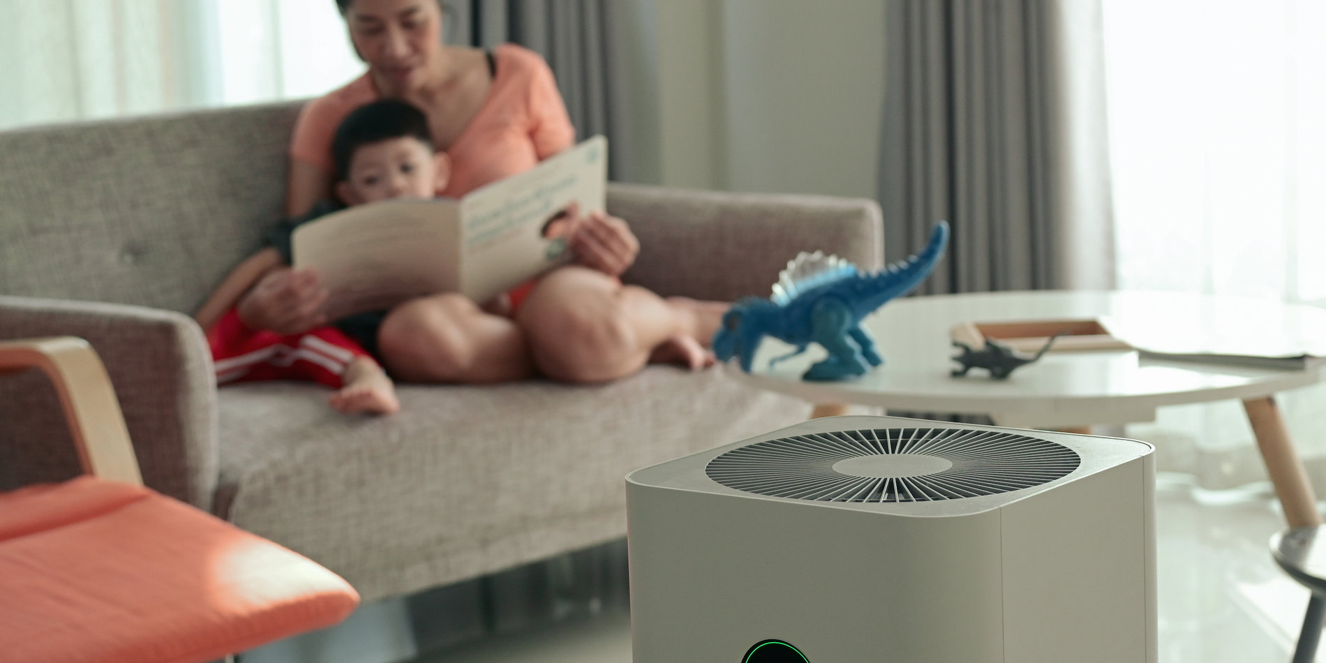 parent and child reading on a couch with air filter in foreground