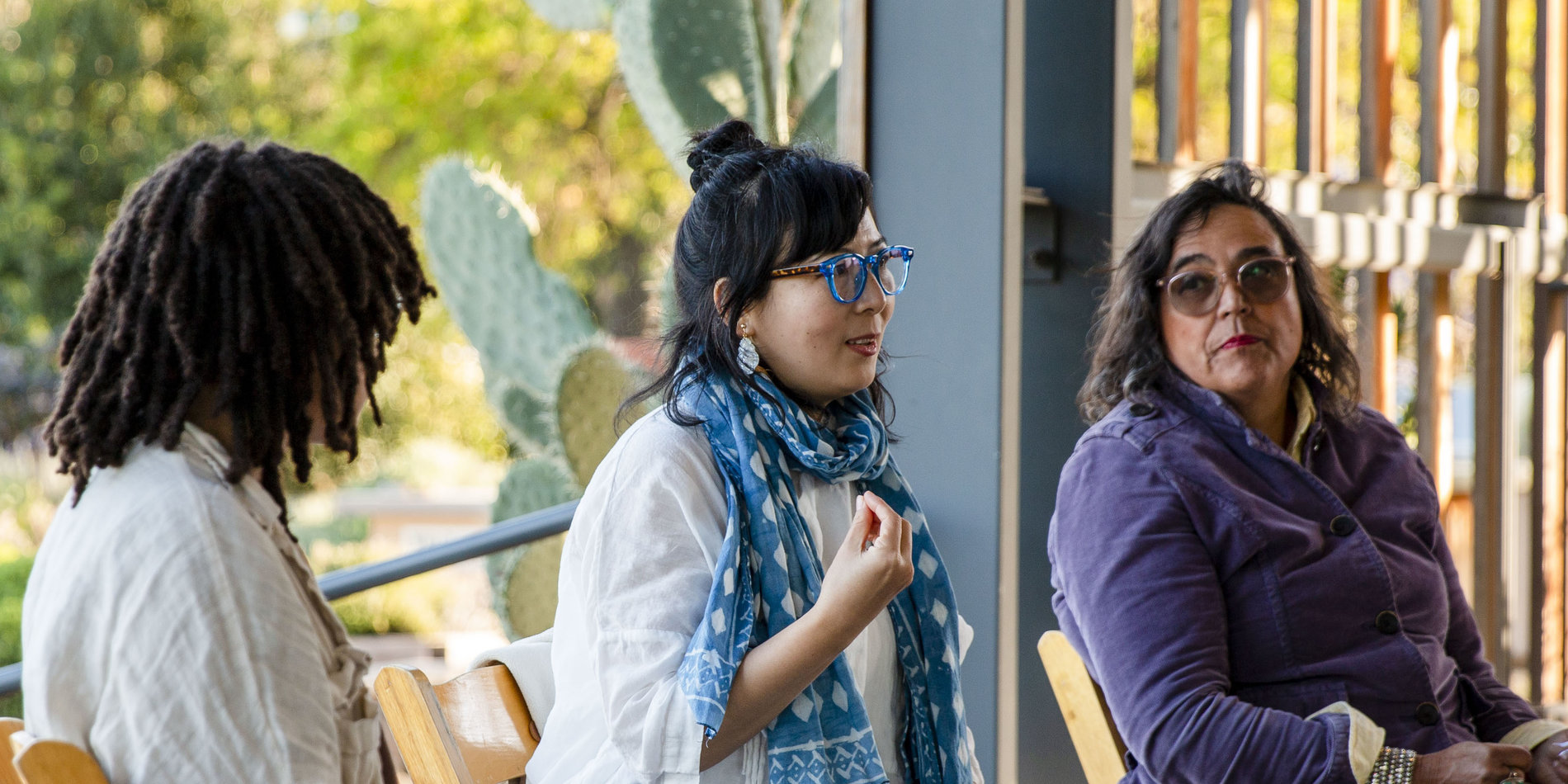Three women sit outdoors talking.