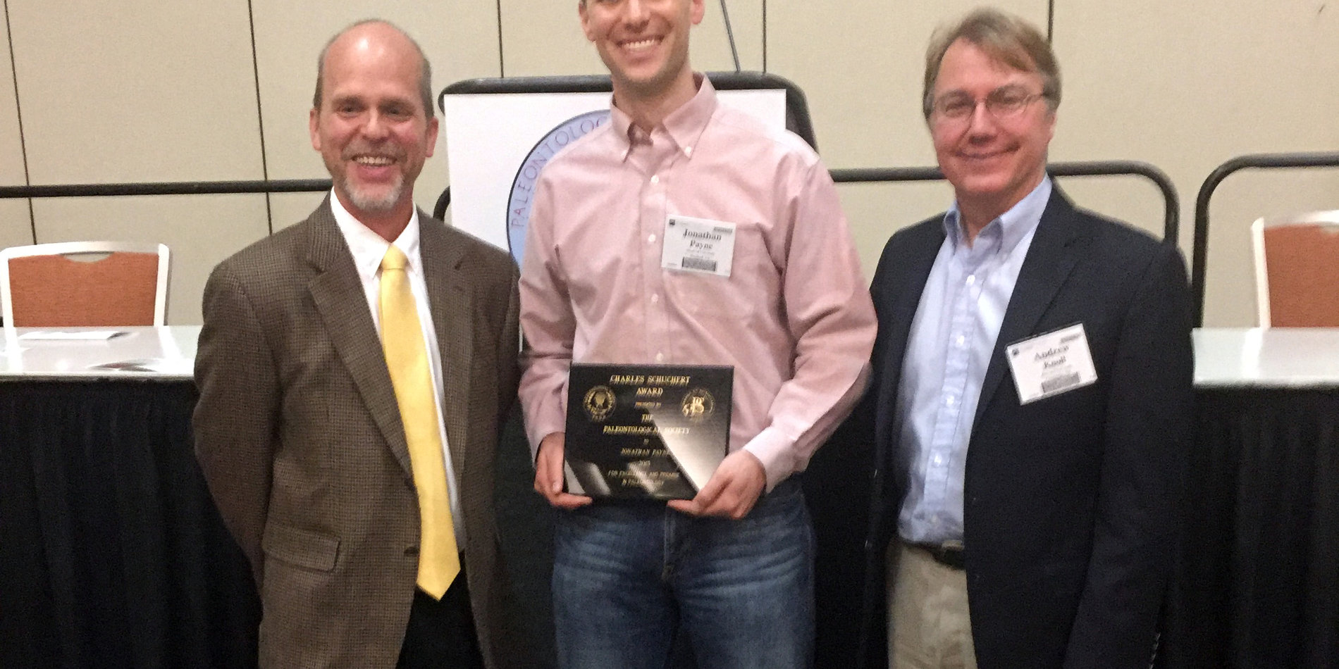 Three men standing with a plaque 