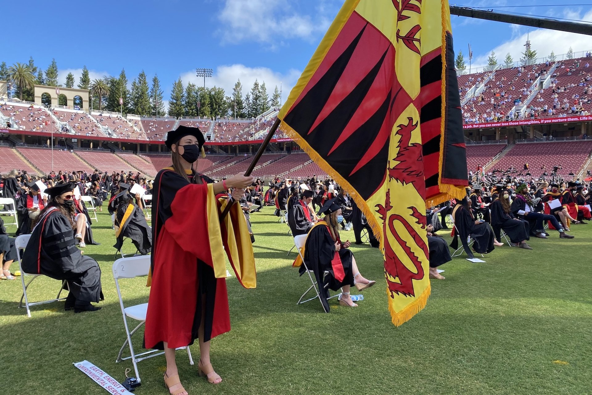 Graduate waving school flag in stadium