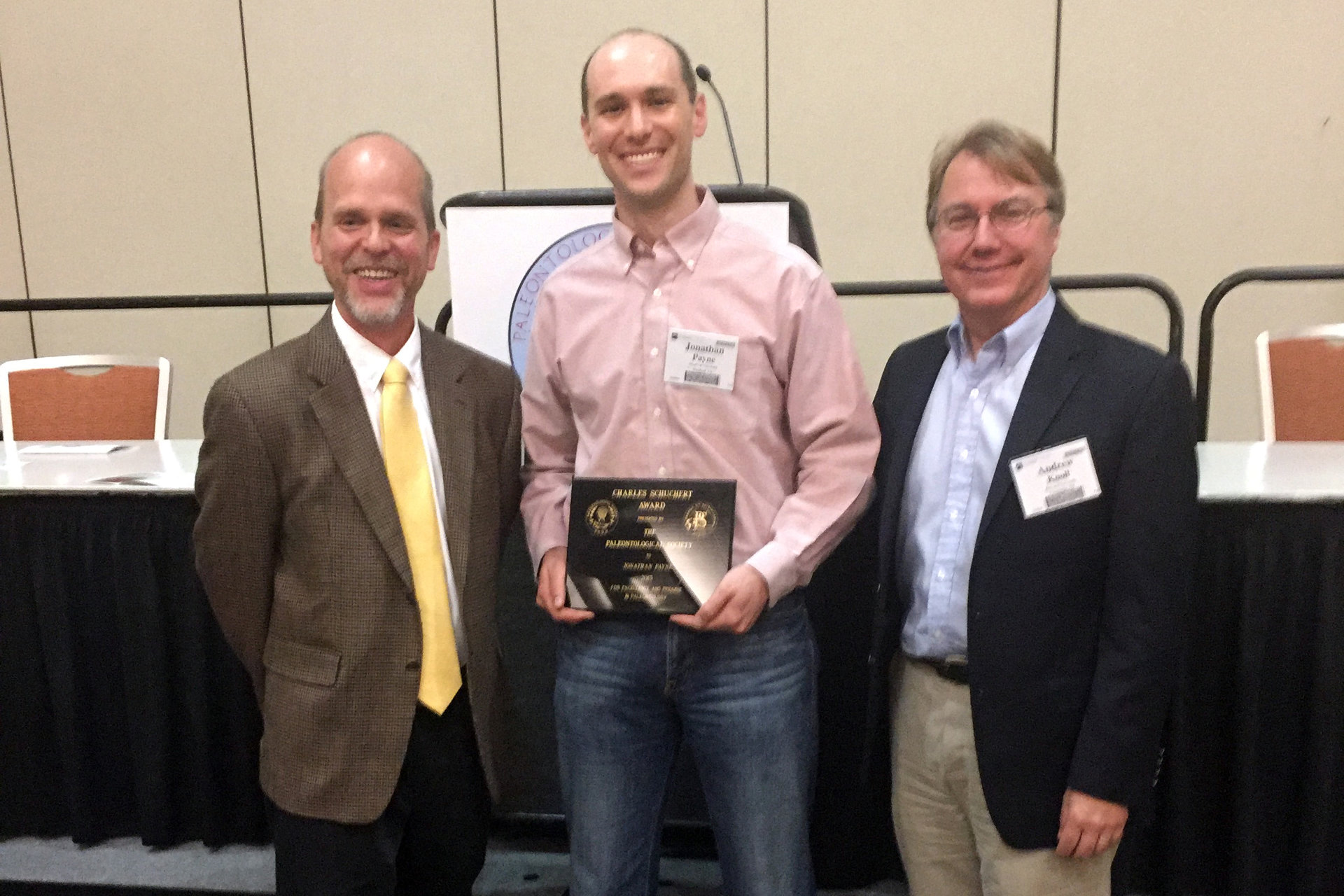 Three men standing with a plaque 
