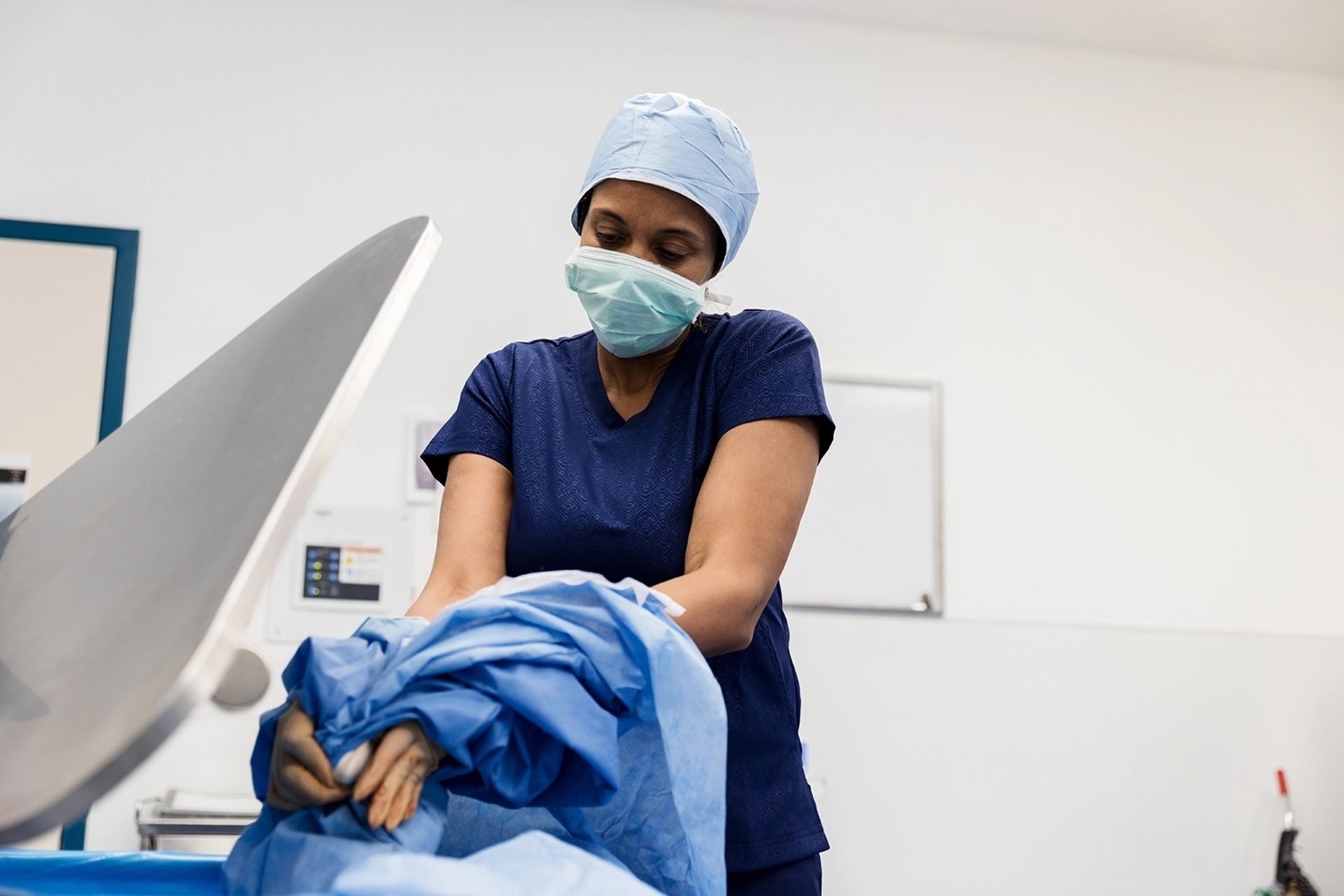 A surgeon puts a surgical gown into a waste bin