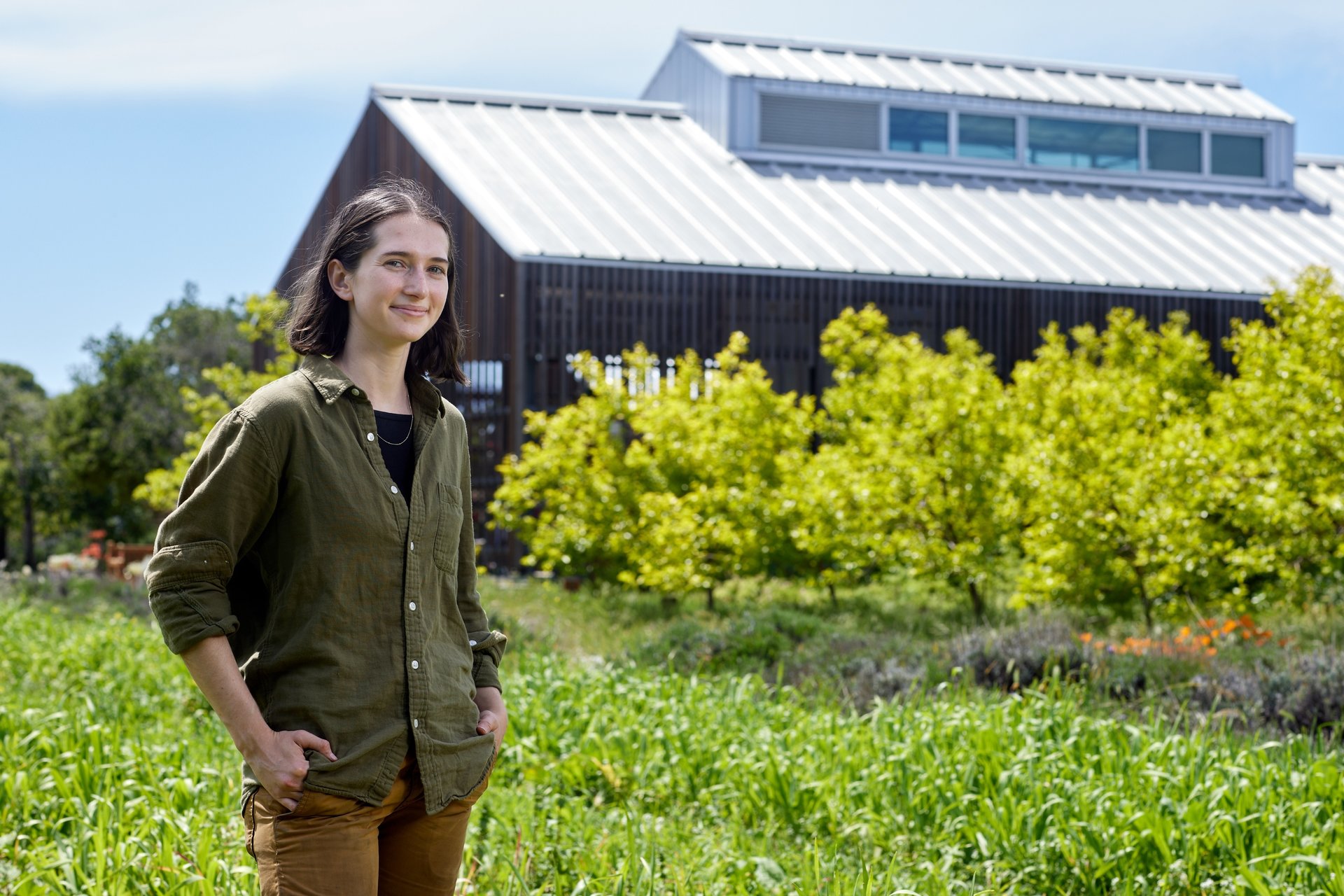 Acacia Lynch smiling at the O'Donohue Family Stanford Educational Farm with the barn in the background