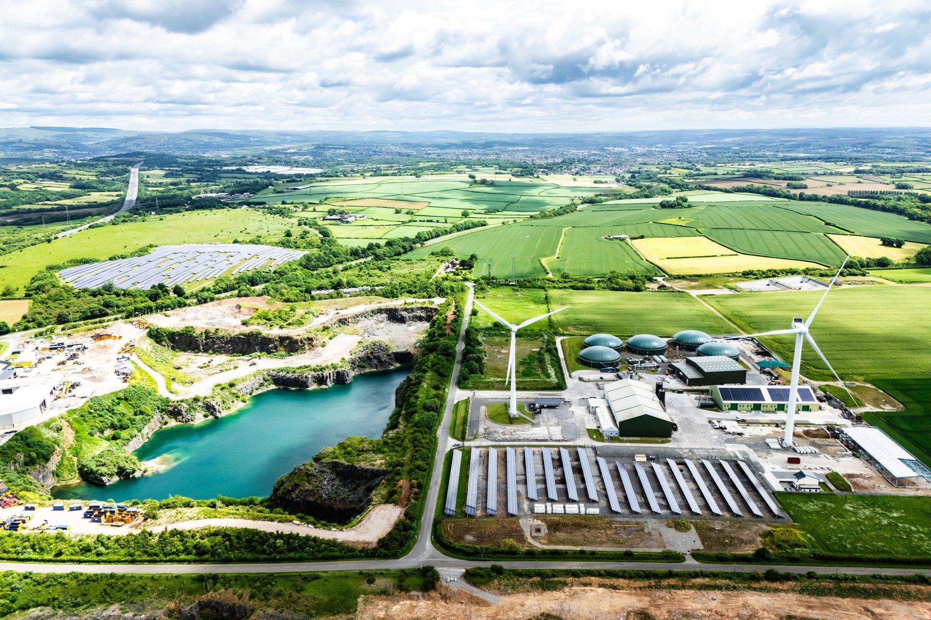 Landscape with wind turbines, rolling green fields, and water
