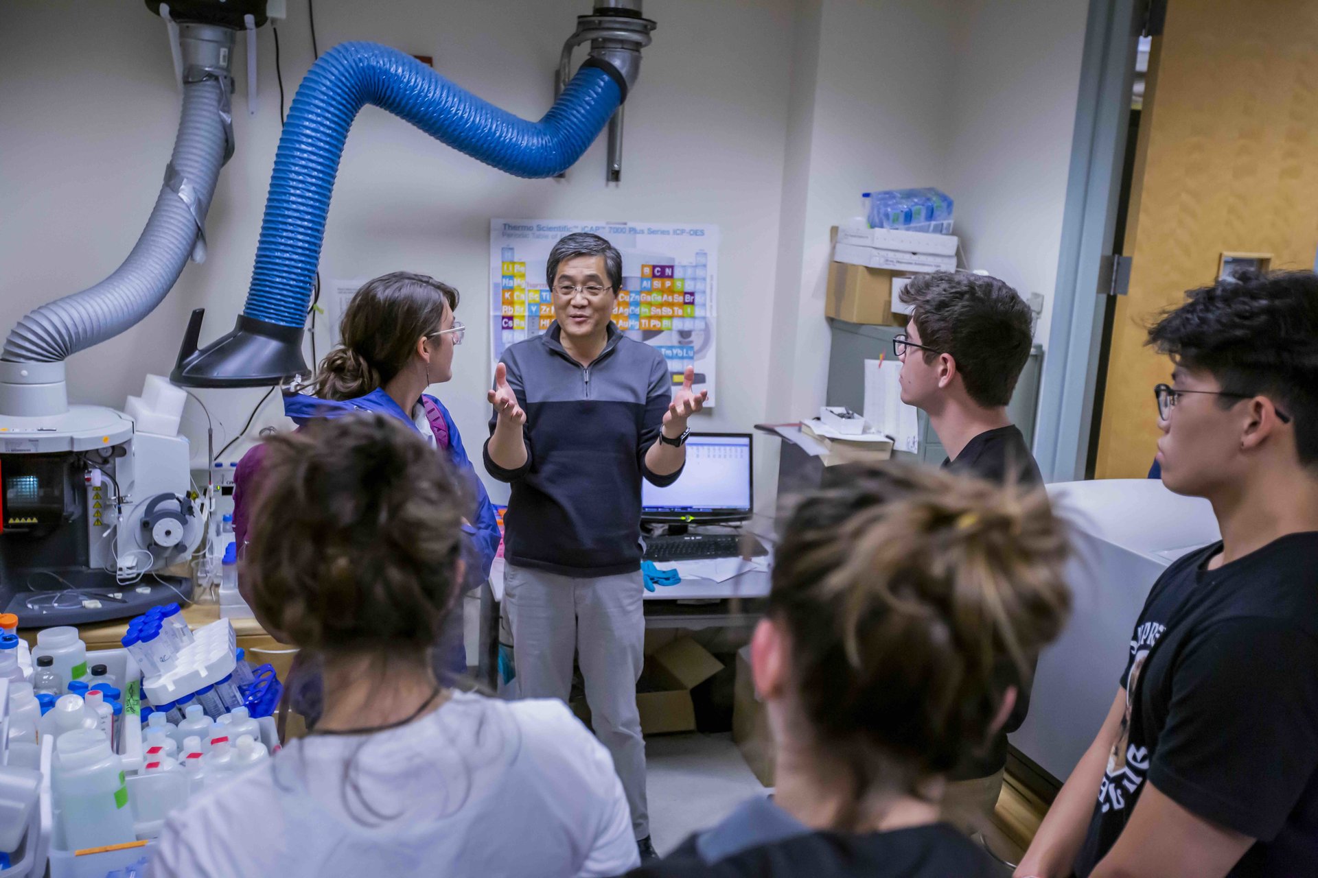 A group of people listening to a researcher speaking in a lab