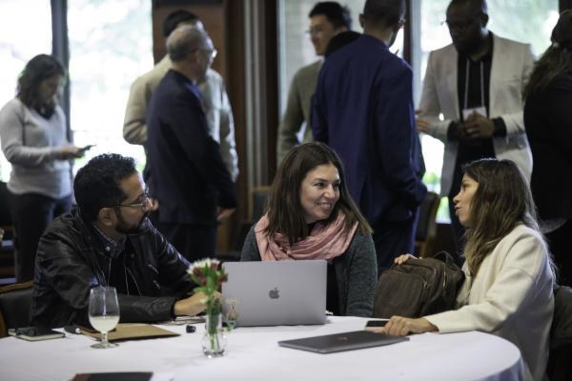 Three people sit at a table talking.