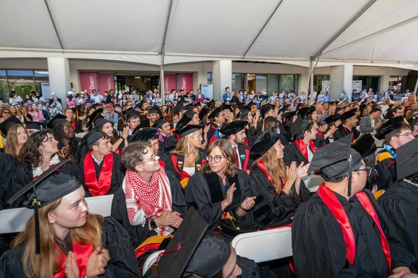 Large audience of graduating students smiling and applauding