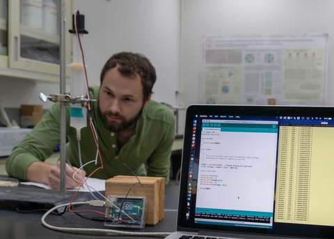 Graduate student, Alex Kendrick, calibrates a sensor in the lab measuring a water level.