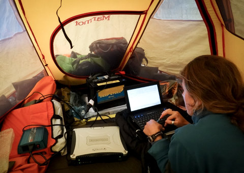 Lauren Oakes analyzes data in a tent.