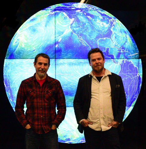 People in front of globe on large screen.