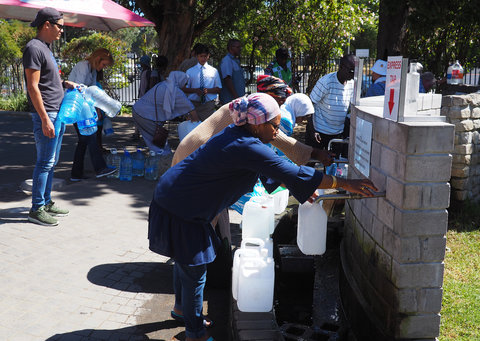 Cape Town citizens filling water bottles at spring