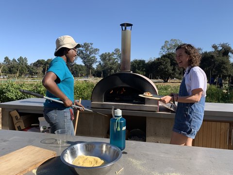 Stanford Roots member Natalie Ezeuqwu (left) working the wood-burning pizza oven for Harvest Festival.