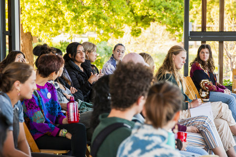 A student sitting in a crowd of people asks a question.