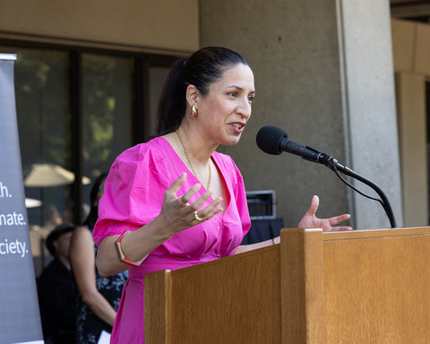 Lupe Carrillo smiling and speaking at a podium outside