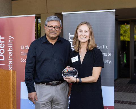 Jenny Skerker smiling on stage holding the Excellence in DEI award with Arun Majumdar