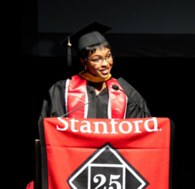 Fatoumata Barrie speaking at a podium wearing a cap and gown