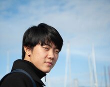 Yuchen Li with a blue sky behind him. 