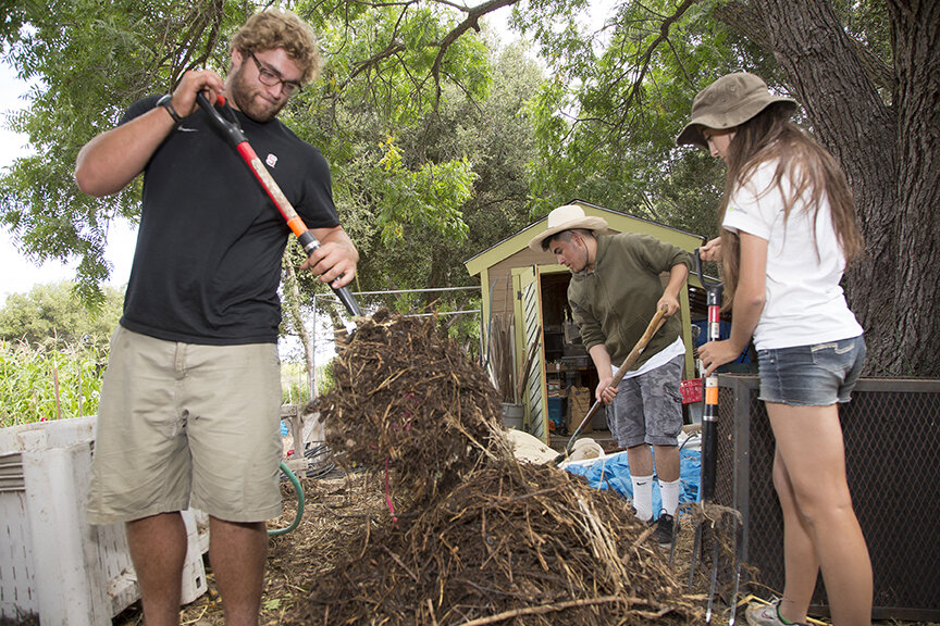 A man and a women working on a compost pile 