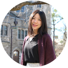 Professor Ching-Yao Lai smiles with a college campus' stone building in the background
